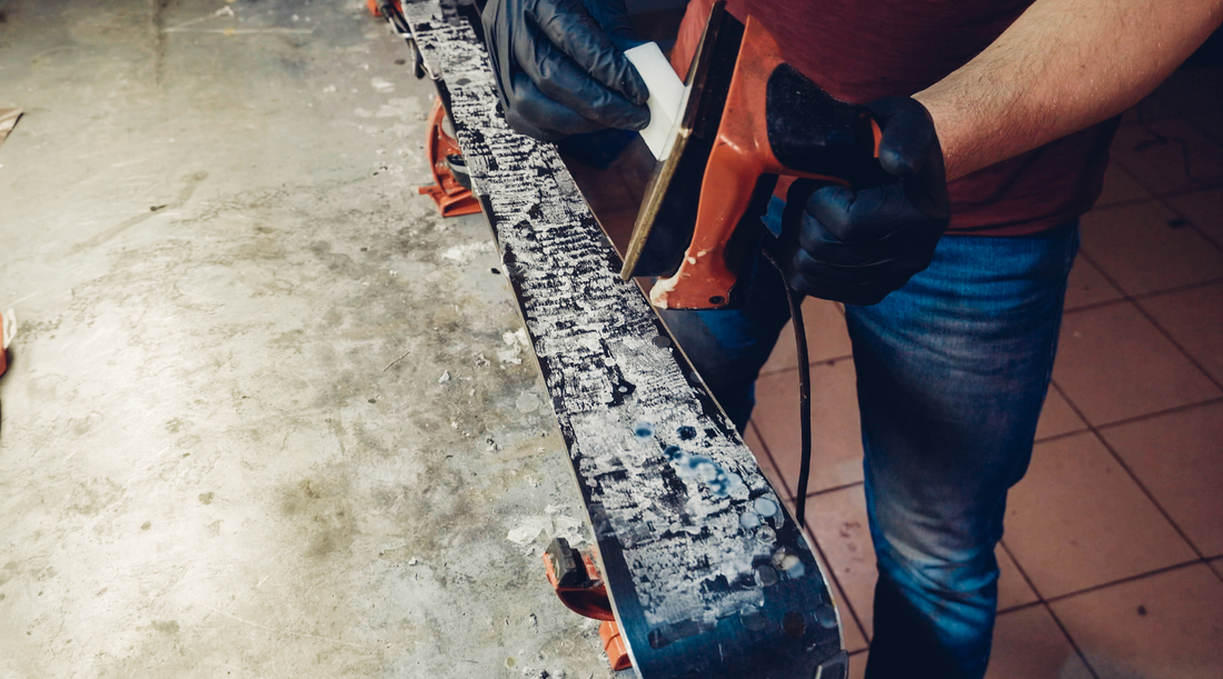 Hot wax is being applied to the bottom of a ski. 